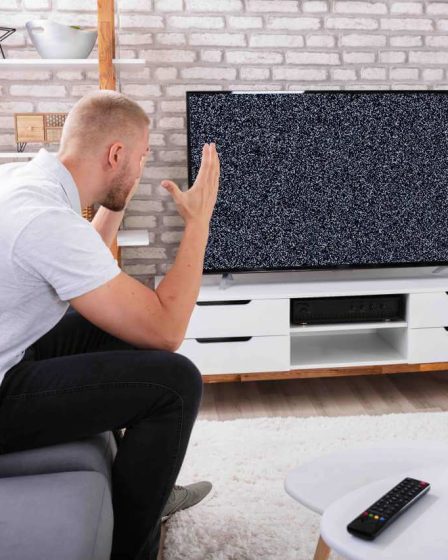 Segnale-TV-assente-uomo-seduto-divano-casa-alza-le-mani-disperato